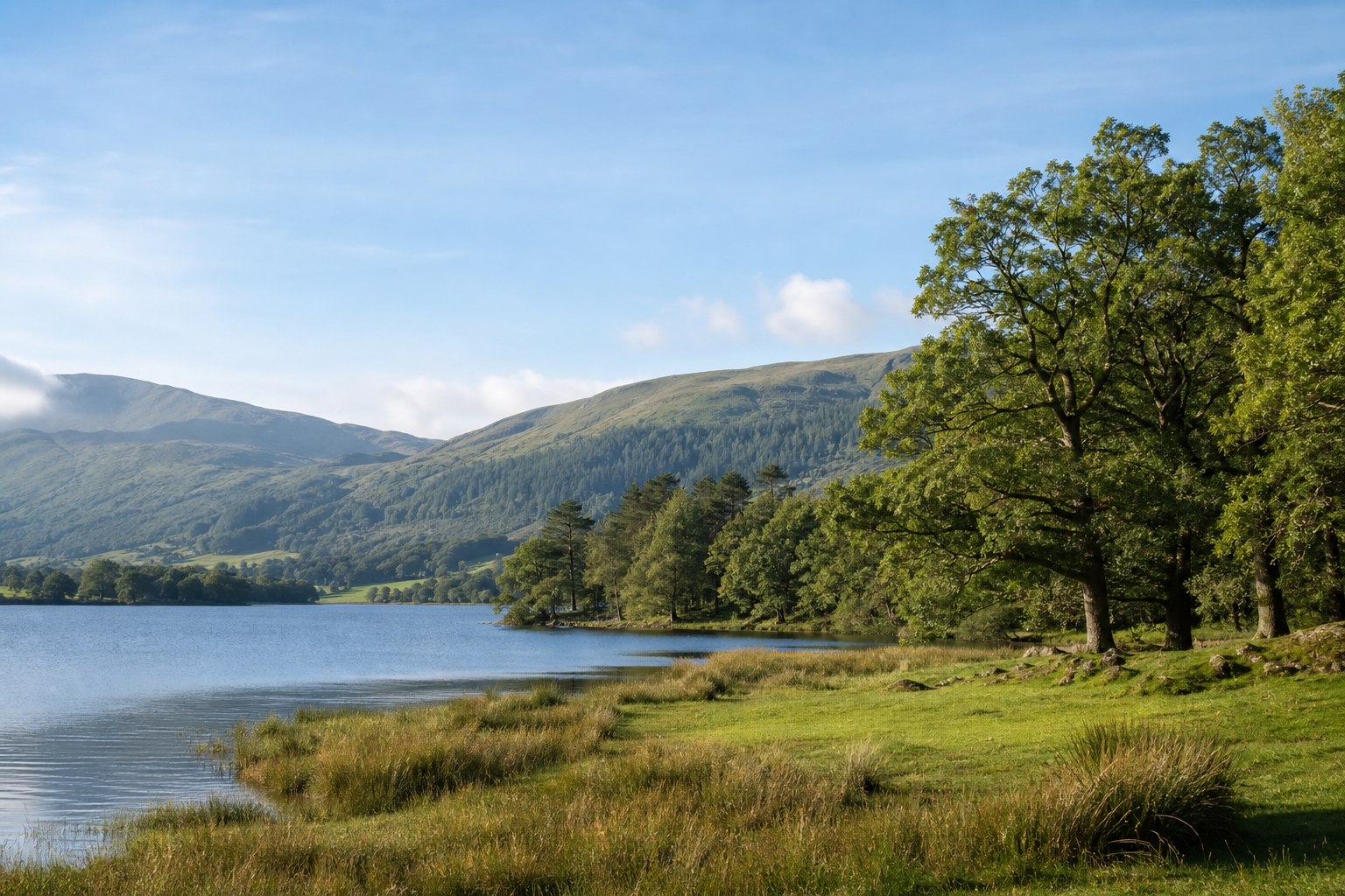 A quiet southern Lake District shoreline beneath layered green fells